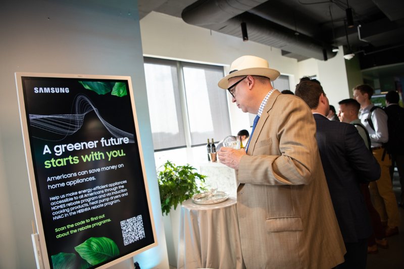 A man in a straw hat reads a Samsung sign titled A greener future starts with you.